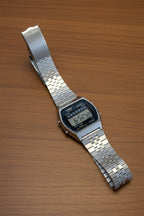 Digital watch with a metal strap on a light gray background