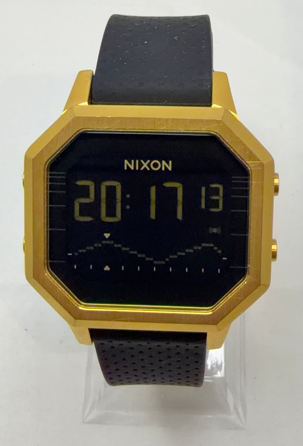 Gold and black digital watch with 'Nixon' branding on a white background