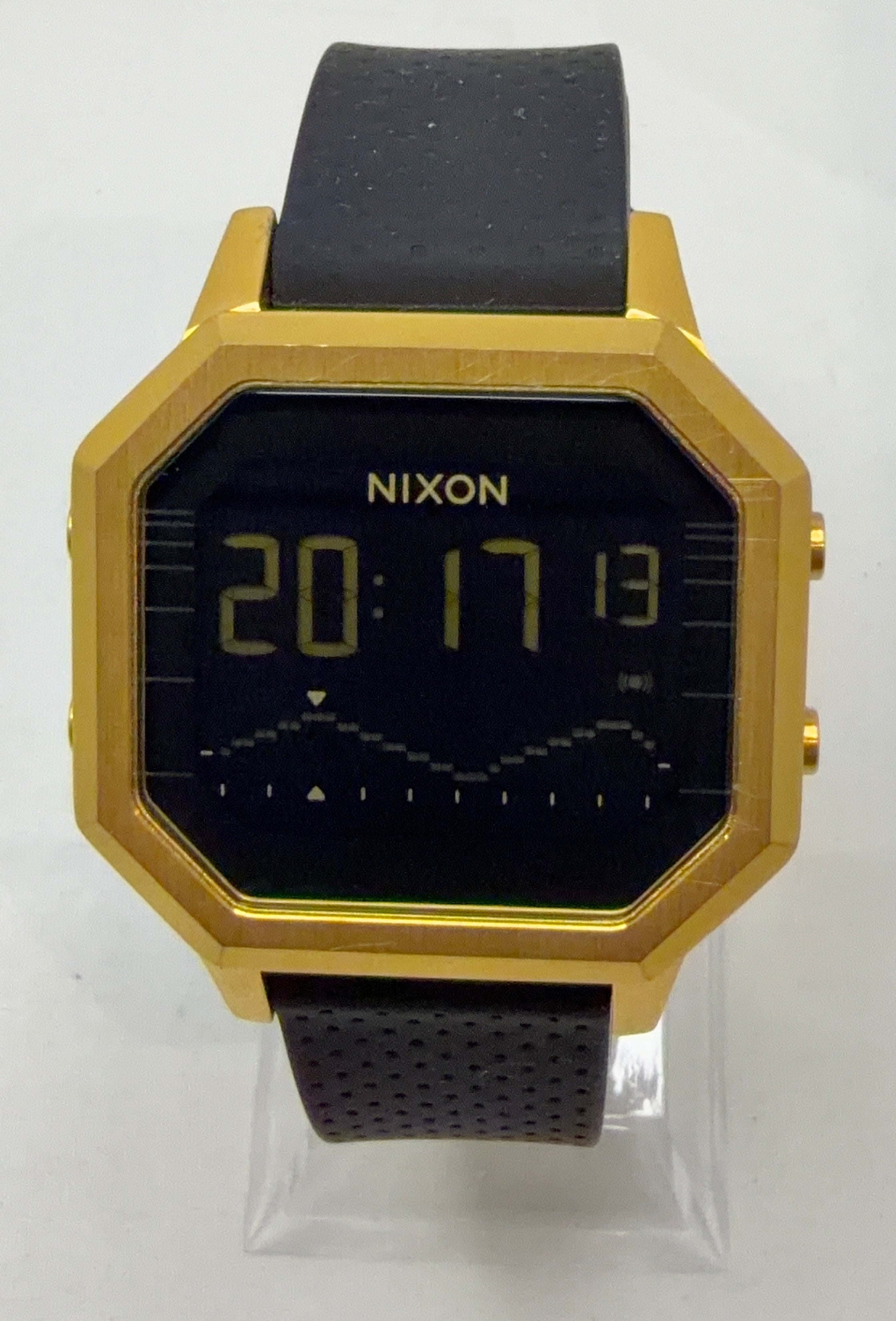 Gold and black digital watch with 'Nixon' branding on a white background