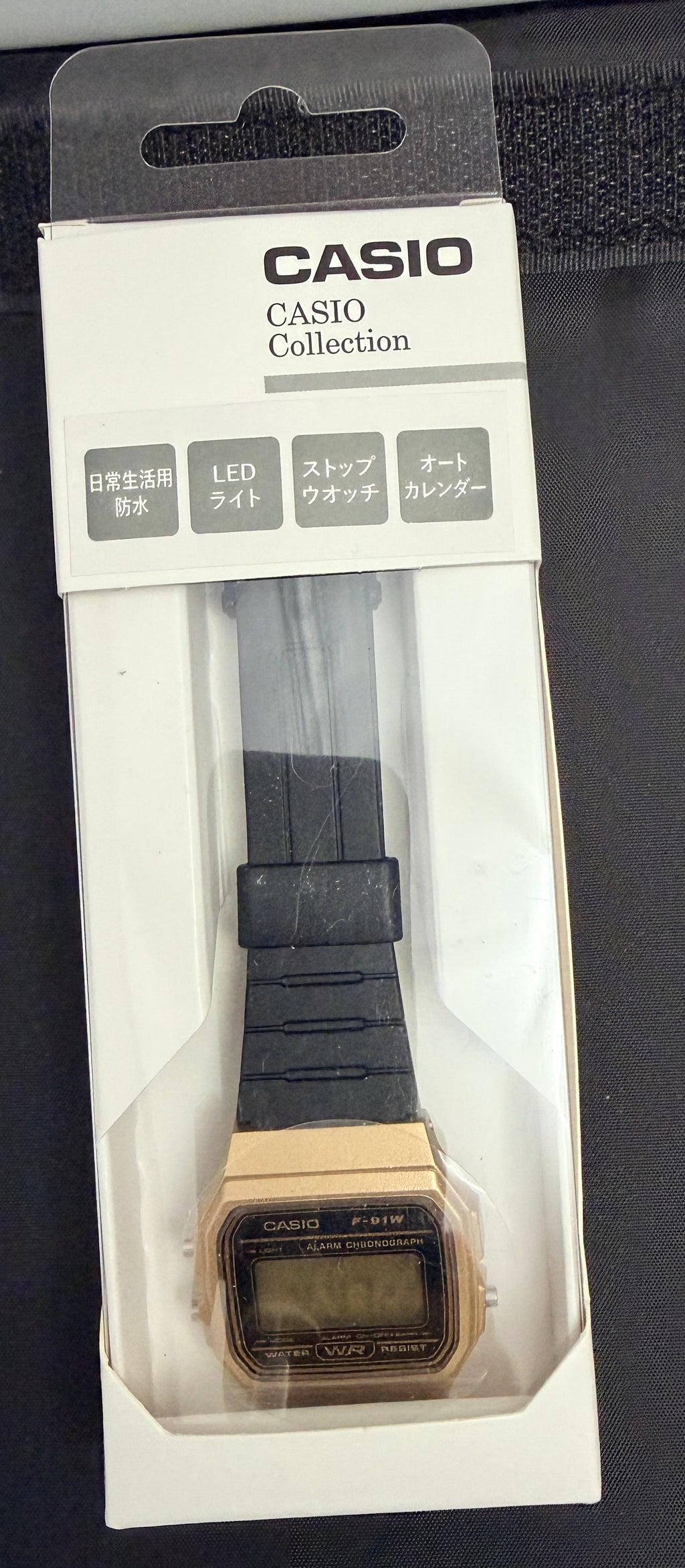 Casio Collection digital watch in its original white and black retail packaging, featuring a gold-tone case and a black strap.