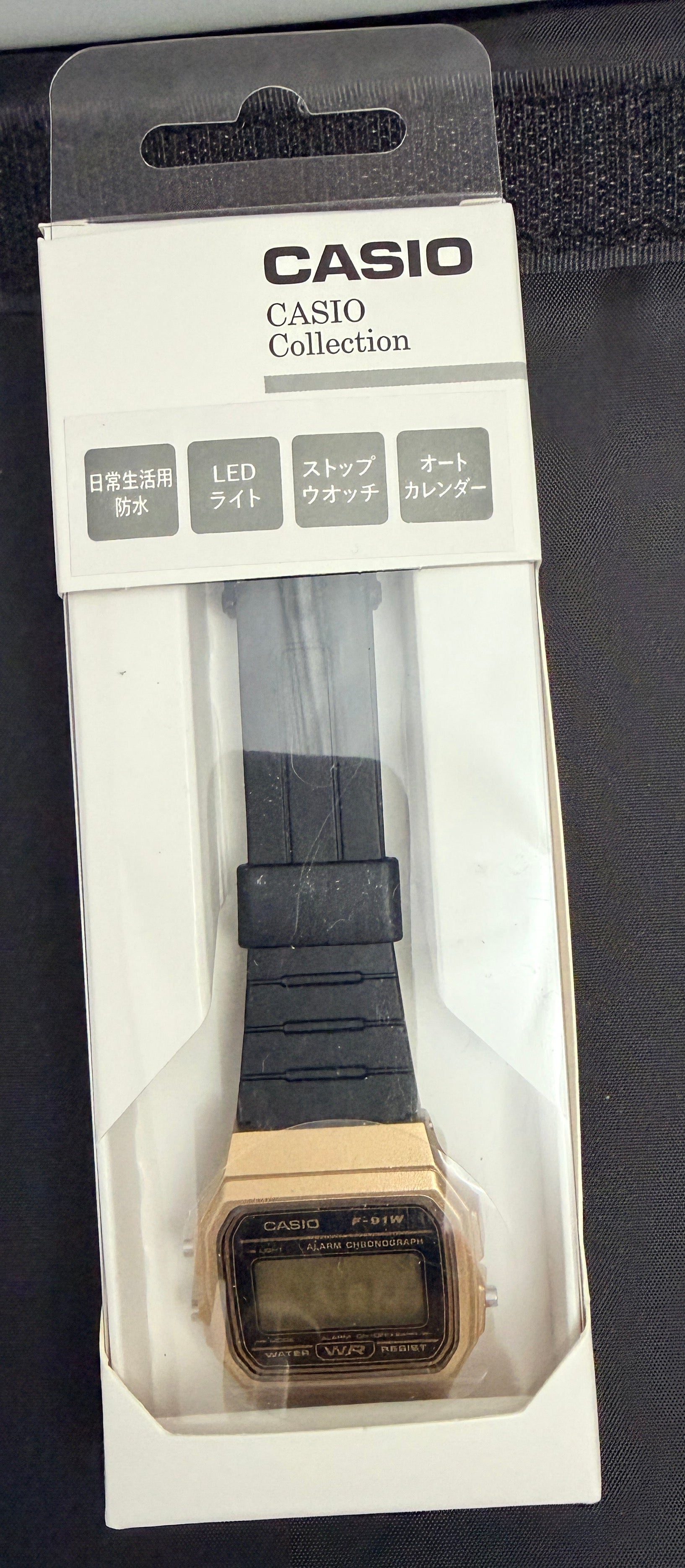 Casio Collection digital watch in its original white and black retail packaging, featuring a gold-tone case and a black strap.