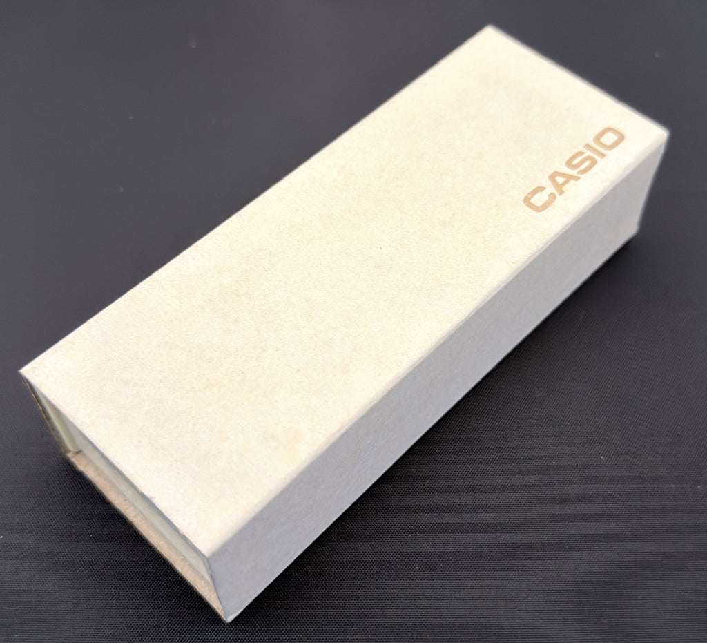A light beige Casio product box with the brand name printed in orange, resting on a dark surface.